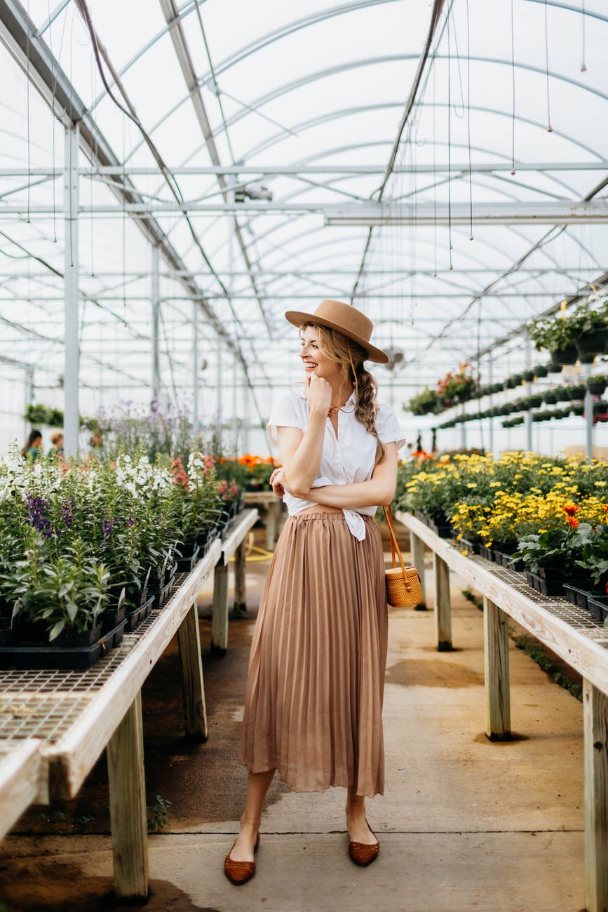 woman in white shirt and brown hat standing in the flower shop